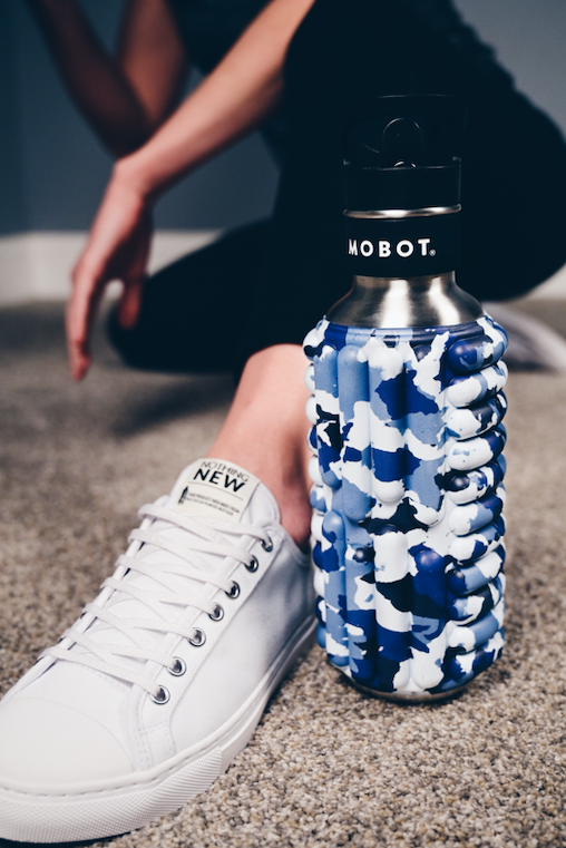 a model sitting on the floor next to marine big bertha 40oz Mobot foam roller water bottle