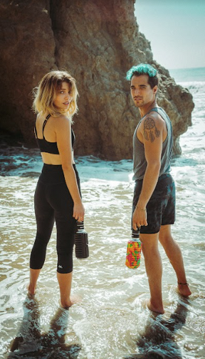 man and woman standing in the ocean with Mobot foam roller water bottles 