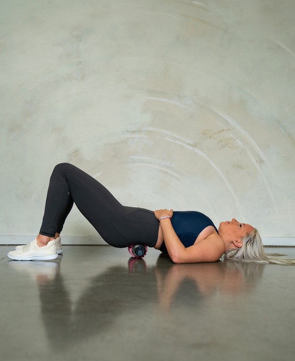 a woman excercising her lower back using Mobot foam roller water bottle 